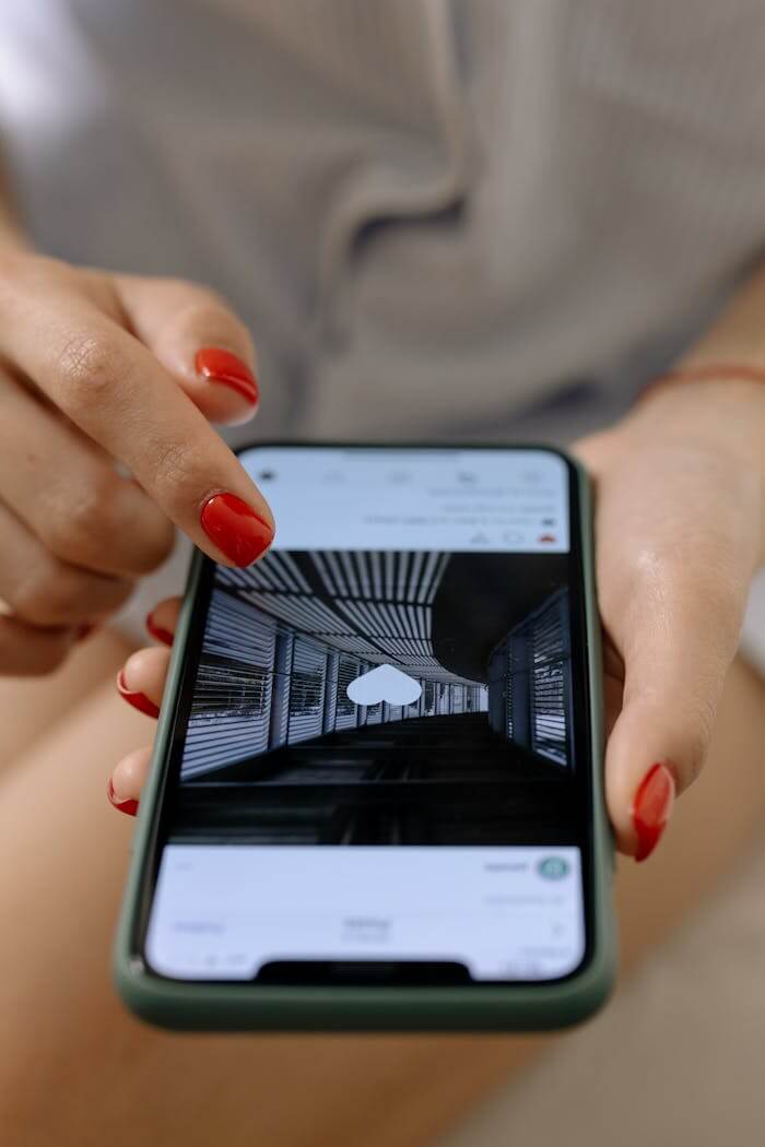 A woman with red nails uses a smartphone to browse social media indoors.